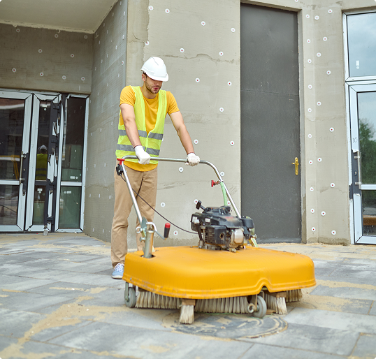 Worker using a professional power sweeper to clean up a construction site