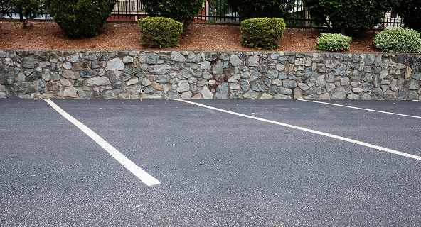A parking lot with fresh asphalt and striping after asphalt maintenance