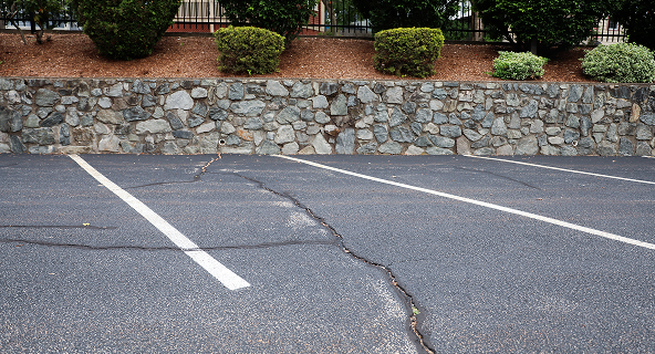 A parking lot with large cracks before repairs