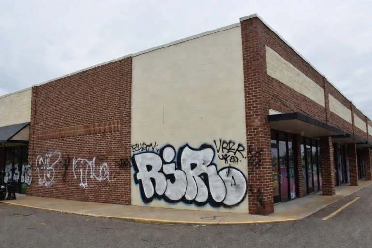 Brick and painted CMU building exterior covered with large black and white graffiti tags