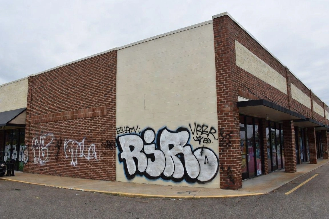 Brick and painted CMU building exterior covered with large black and white graffiti tags