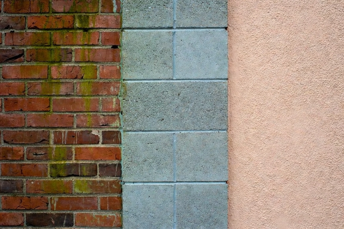 Three wall textures: mossy red brick, gray concrete blocks, and beige stucco