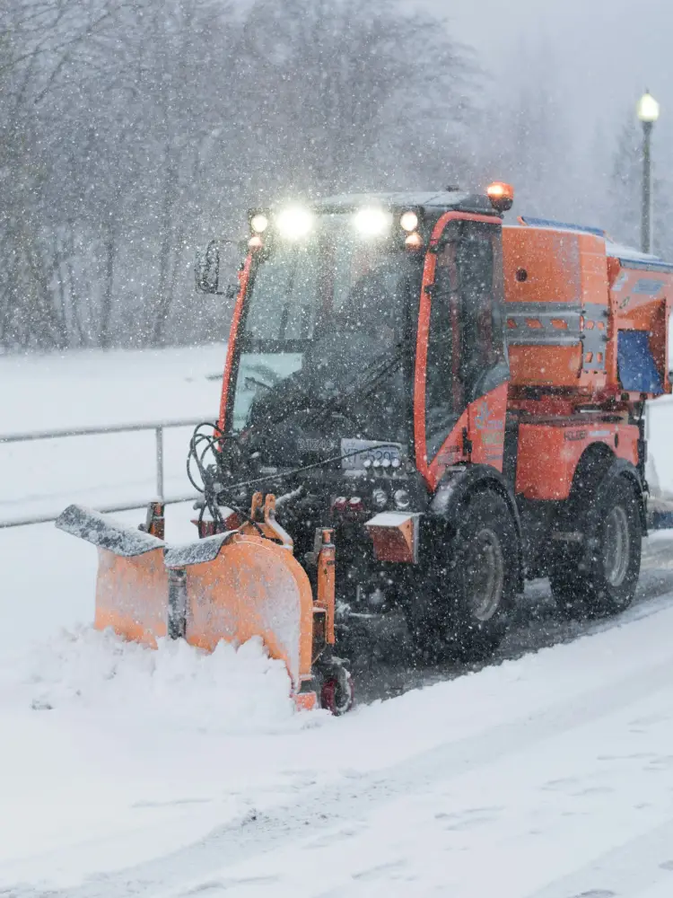 Compact snow plow clearing a walkway at a Raleigh commercial property